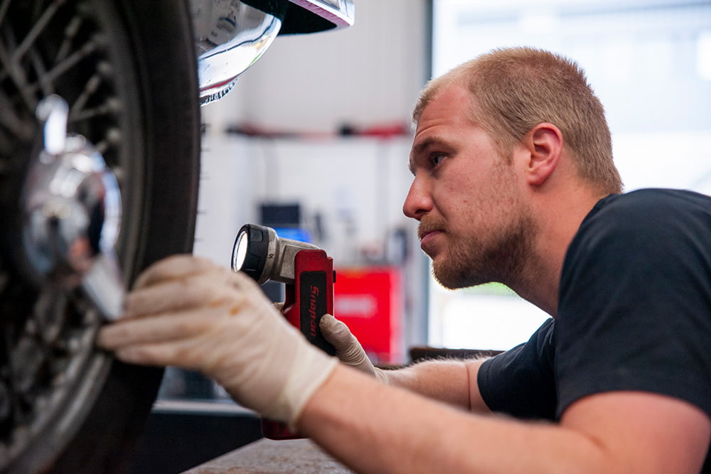 mechanic inspecting tyres on car