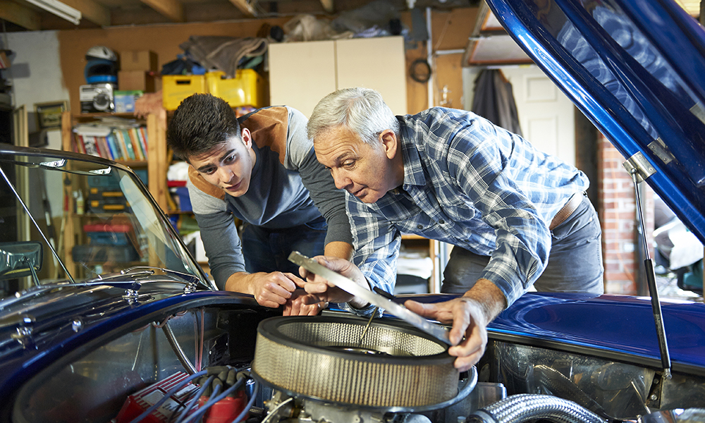 young and old man fixing engine in garage