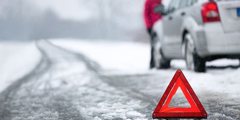Car pulled up on the side of a snowy road, with warning triangle for safety