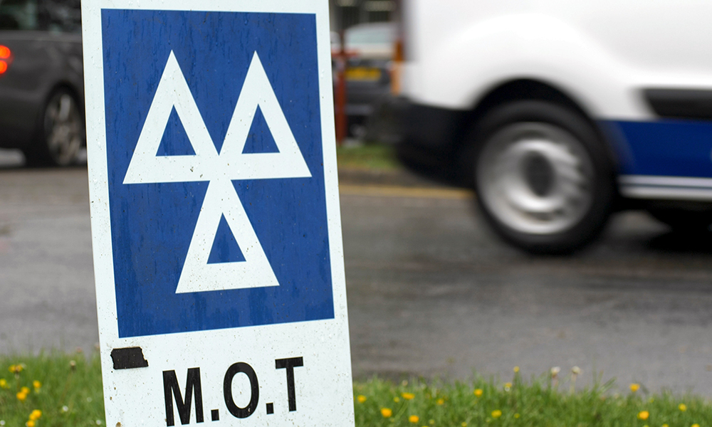 mot test sign on roadside with van driving by