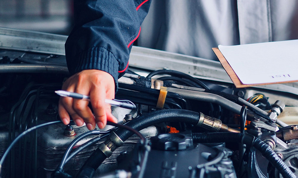 mechanic with clipboard inspecting the components of car