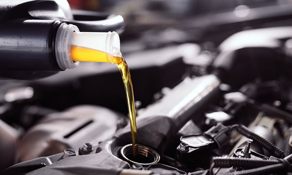 car mechanic pouring in engine oil